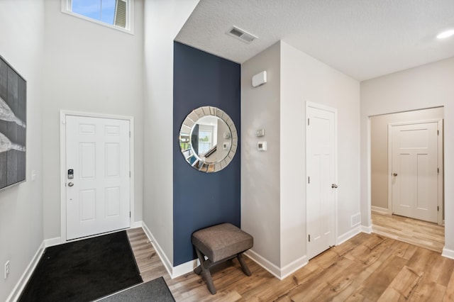 foyer entrance featuring baseboards, visible vents, and light wood-type flooring