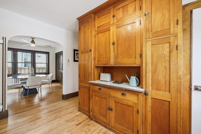 2170 Palace Ave, Saint Paul, MN 55105 - kitchen featuring brown cabinets, light countertops, arched walkways, light wood-style flooring, and a ceiling fan
