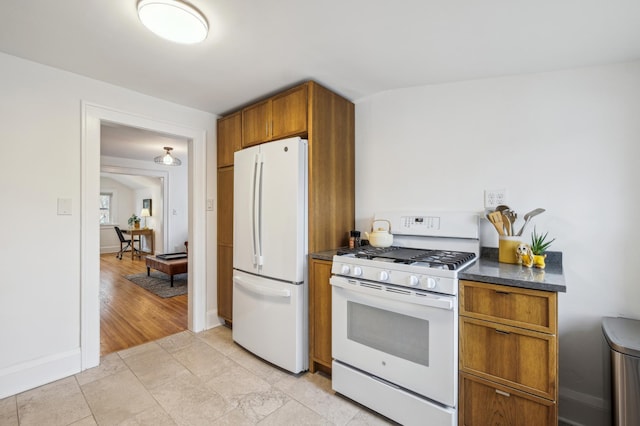 2170 Palace Ave, Saint Paul, MN 55105 - kitchen featuring dark countertops, baseboards, brown cabinetry, and white appliances