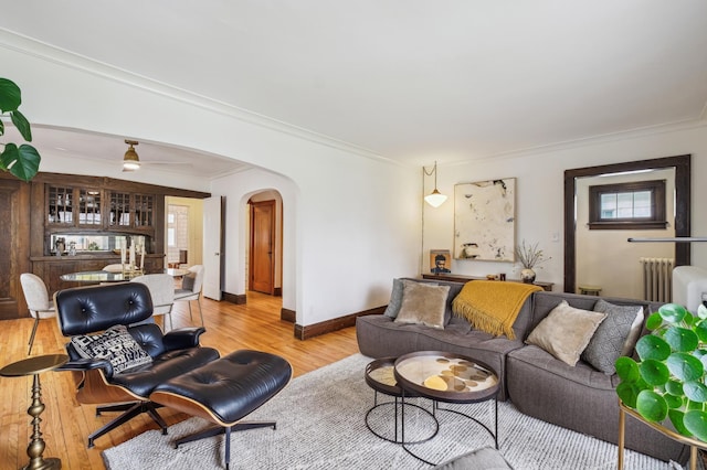 2170 Palace Ave, Saint Paul, MN 55105 - living room featuring arched walkways, ornamental molding, radiator heating unit, and light wood-style floors