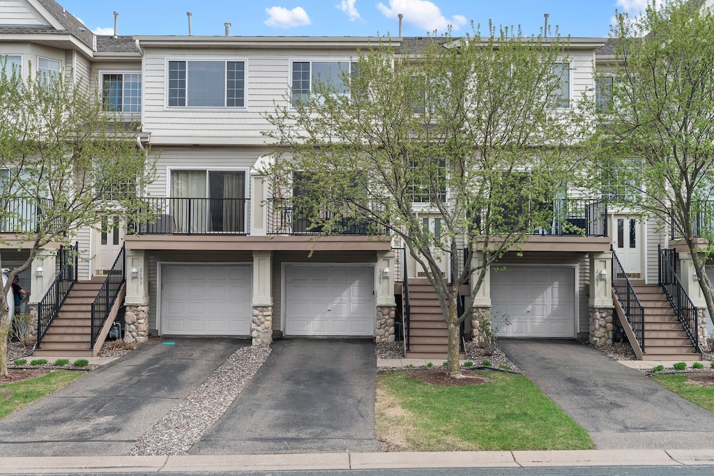 view of property featuring a garage, stairs, driveway, and stone siding