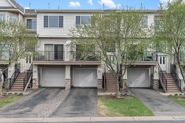 view of property featuring a garage, stairs, driveway, and stone siding