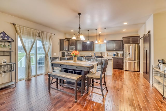 dining space with recessed lighting, a barn door, and light wood finished floors