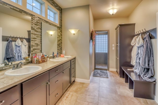 bathroom featuring double vanity, a sink, baseboards, and a shower stall