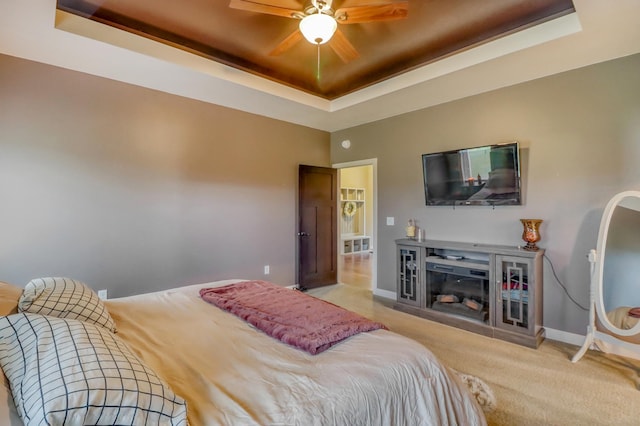bedroom with a ceiling fan, a fireplace, baseboards, a raised ceiling, and carpet flooring