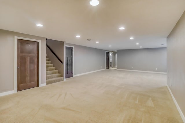finished basement with stairway, baseboards, light carpet, and recessed lighting