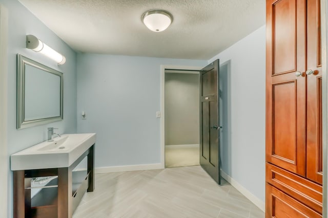 bathroom with baseboards, vanity, and a textured ceiling