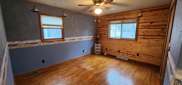 unfurnished room featuring a textured ceiling, ceiling fan, visible vents, and wood finished floors