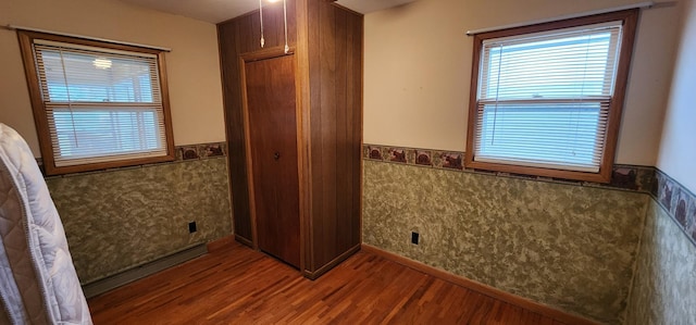 unfurnished bedroom featuring a wainscoted wall and wood finished floors
