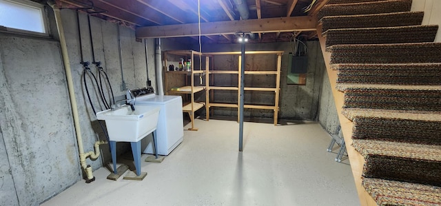 unfinished basement featuring washing machine and clothes dryer, a sink, and electric panel