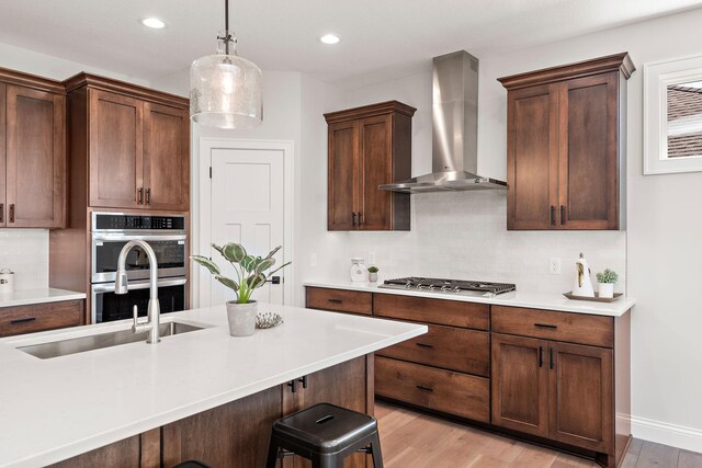 7521 Ocean Ave, Otsego, MN 55330 - kitchen featuring light countertops, wall chimney exhaust hood, light wood finished floors, backsplash, and stainless steel appliances