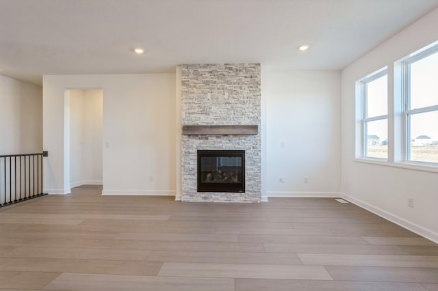 unfurnished living room with recessed lighting, baseboards, wood finished floors, and a fireplace
