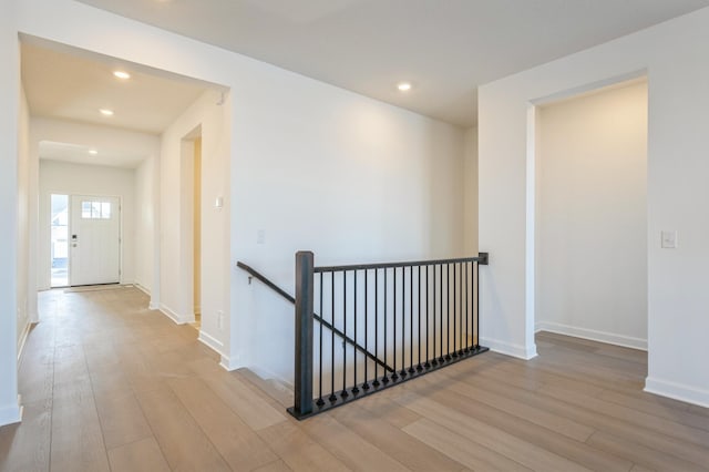 corridor featuring recessed lighting, baseboards, wood finished floors, and an upstairs landing