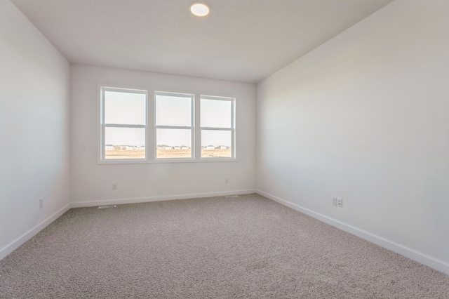 spare room with baseboards and light colored carpet