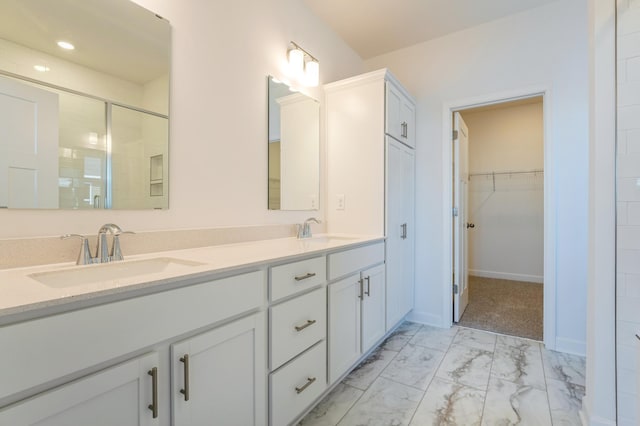 bathroom with double vanity, a sink, marble finish floor, and a stall shower