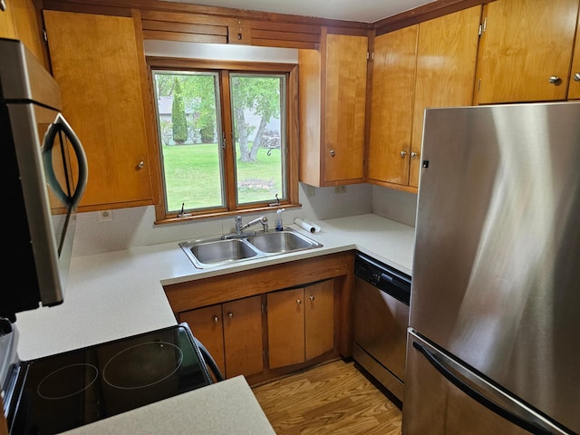 kitchen featuring appliances with stainless steel finishes, a sink, light countertops, and brown cabinets