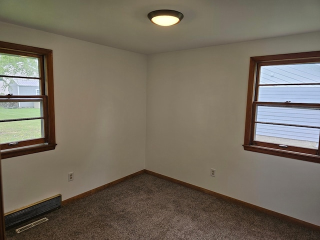 unfurnished room featuring dark colored carpet and baseboards
