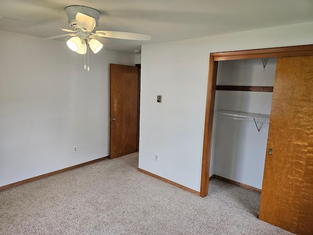 unfurnished bedroom with a closet, light carpet, baseboards, and ceiling fan