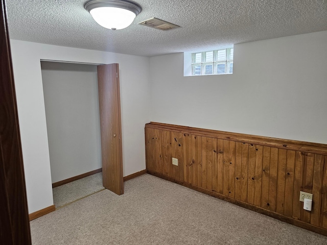 basement featuring a textured ceiling and light colored carpet