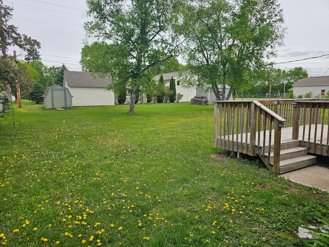 view of green lawn with a deck, a storage unit, and an outdoor structure