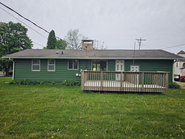 back of property with a chimney, a deck, and a yard