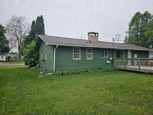 rear view of house featuring a chimney, a wooden deck, and a yard