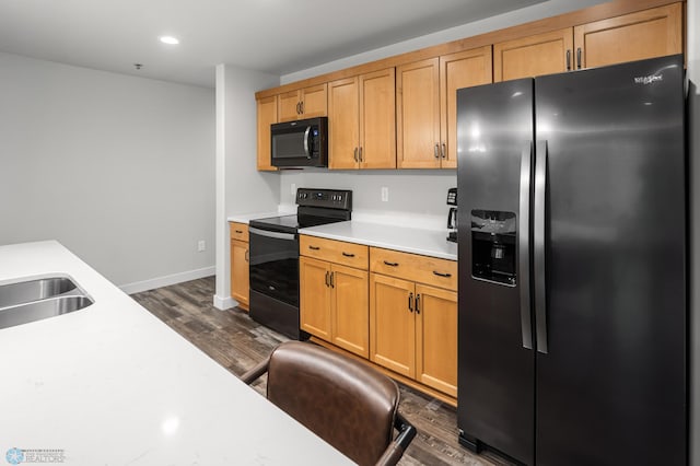 kitchen featuring dark wood-style flooring, light countertops, baseboards, black appliances, and recessed lighting