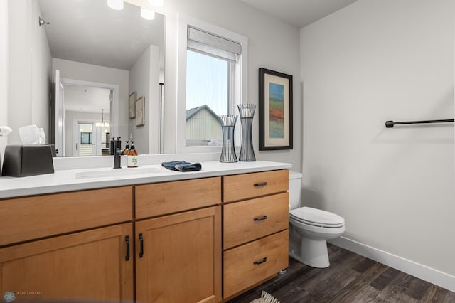 bathroom featuring toilet, baseboards, wood finished floors, and vanity