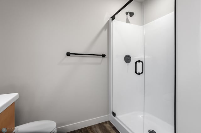 bathroom with vanity, baseboards, a stall shower, and wood finished floors