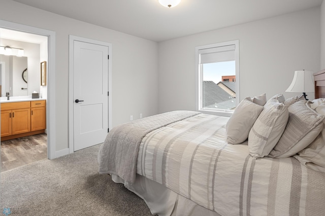 bedroom featuring a sink, baseboards, connected bathroom, and light colored carpet