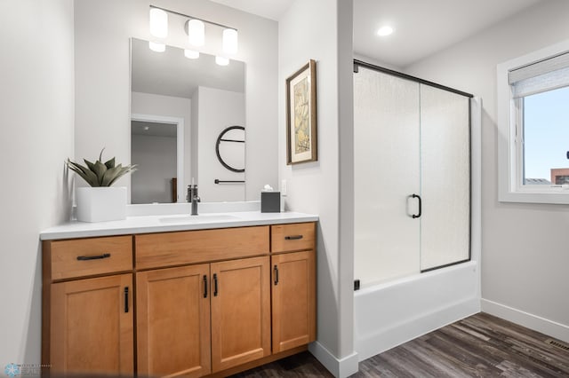 full bath with baseboards, enclosed tub / shower combo, wood finished floors, and vanity