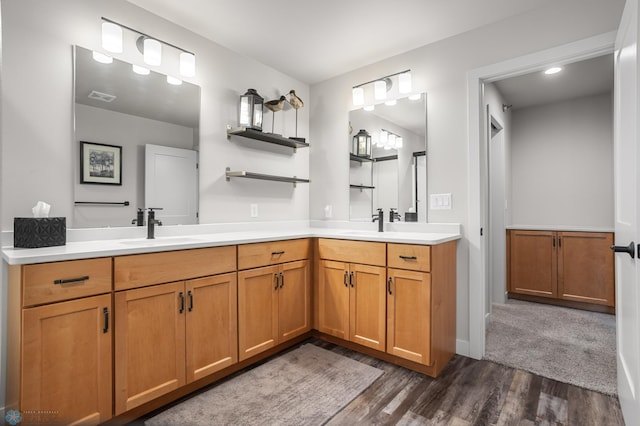 full bath featuring double vanity, visible vents, a sink, and wood finished floors