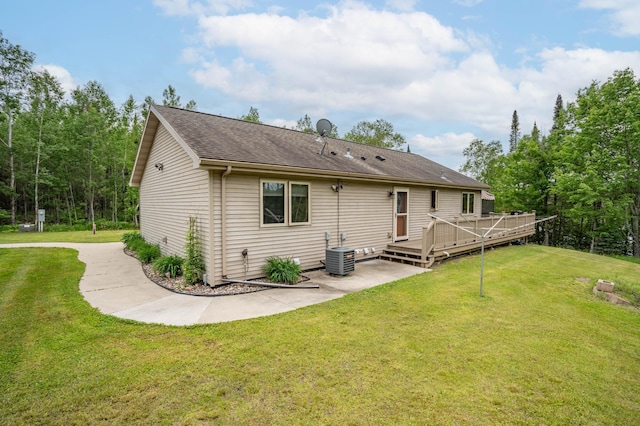 back of house featuring a wooden deck, roof with shingles, a patio area, central air condition unit, and a yard