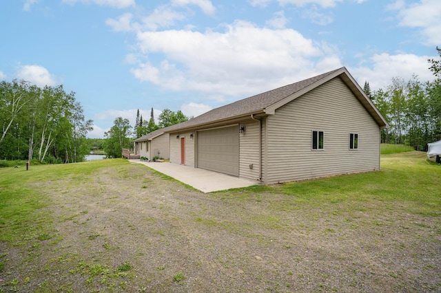view of side of home with a garage, a water view, and a yard