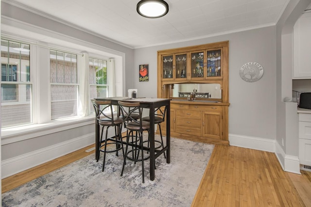 1449 Laurel Ave, Saint Paul, MN 55104 - dining space with arched walkways, baseboards, crown molding, and light wood-style flooring