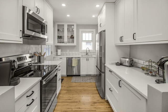 1449 Laurel Ave, Saint Paul, MN 55104 - kitchen featuring appliances with stainless steel finishes, a sink, recessed lighting, light wood-type flooring, and white cabinetry