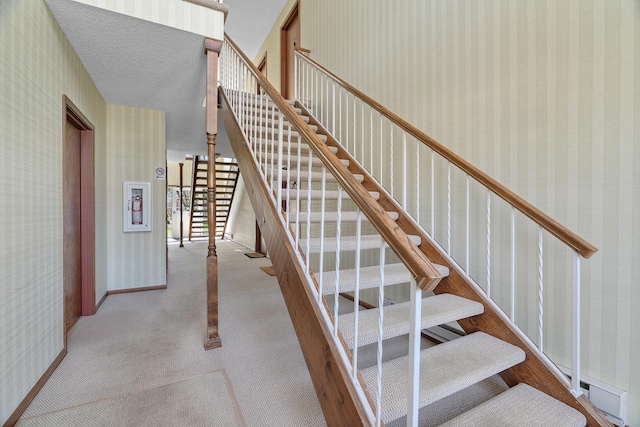 stairway featuring baseboards, carpet floors, and wallpapered walls