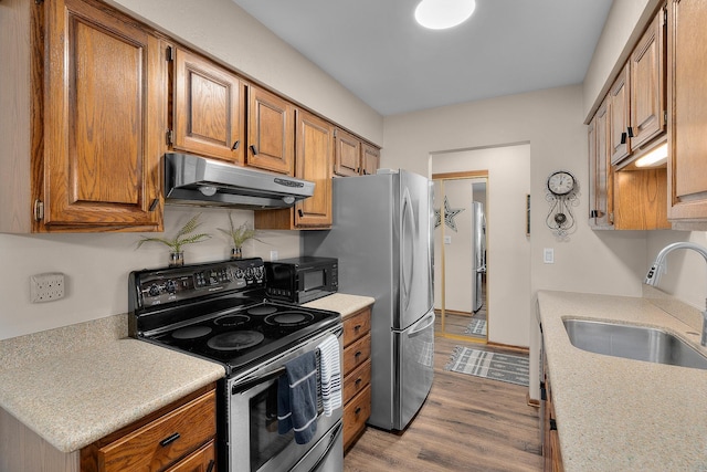 kitchen with black microwave, a sink, light countertops, range with electric cooktop, and under cabinet range hood