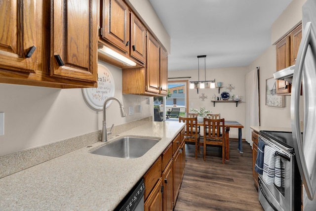 kitchen with brown cabinets, a sink, dark wood finished floors, appliances with stainless steel finishes, and hanging light fixtures