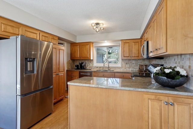 17725 26th Ave N, Plymouth, MN 55447 - kitchen featuring a peninsula, tasteful backsplash, a sink, light wood finished floors, and stainless steel appliances