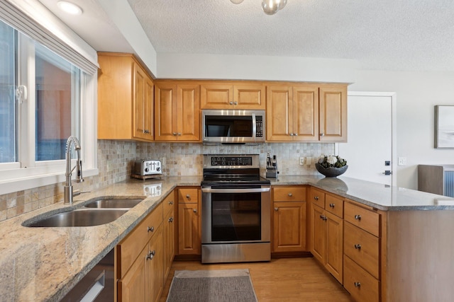 17725 26th Ave N, Plymouth, MN 55447 - kitchen with a peninsula, light stone countertops, appliances with stainless steel finishes, and a sink