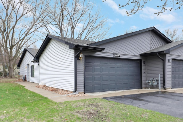 view of property exterior featuring an attached garage, roof with shingles, and driveway