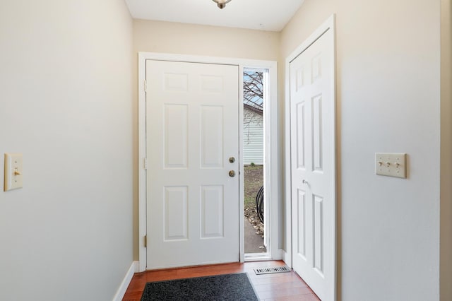 doorway featuring baseboards and wood finished floors