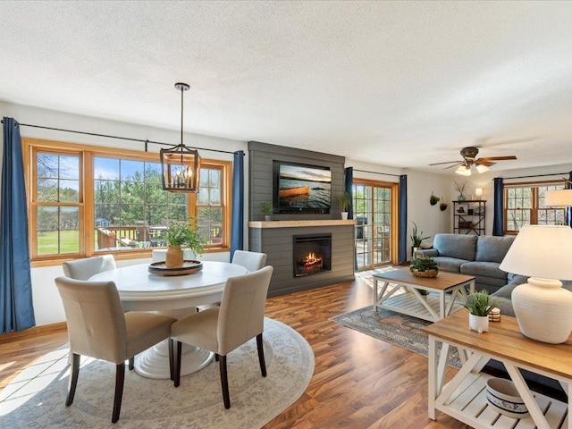 14898 Lynndale Ln, Baxter, MN 56425 - dining space featuring a textured ceiling, a large fireplace, wood finished floors, and a ceiling fan