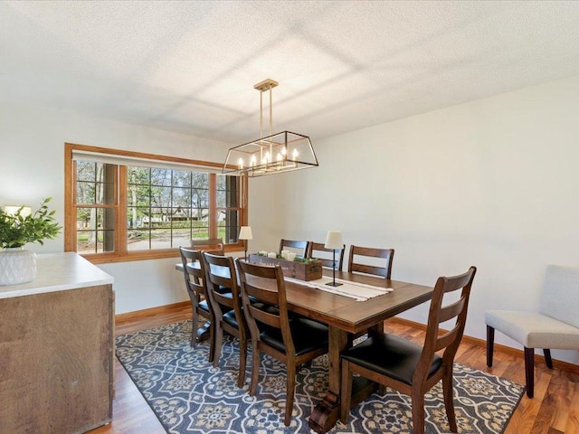 14898 Lynndale Ln, Baxter, MN 56425 - dining space featuring a chandelier, wood finished floors, a textured ceiling, and baseboards