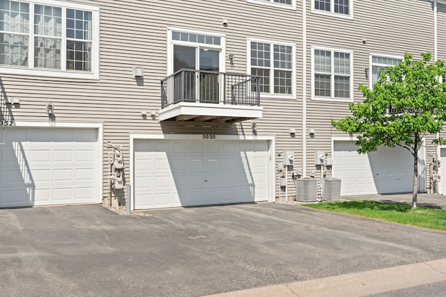 5030 Yuma Ln N, Plymouth, MN 55446 - rear view of property featuring driveway, a garage, a balcony, and cooling unit