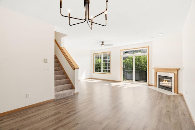 5030 Yuma Ln N, Plymouth, MN 55446 - unfurnished living room featuring wood finished floors, stairway, a fireplace with flush hearth, and a chandelier