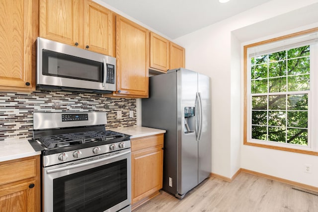 5030 Yuma Ln N, Plymouth, MN 55446 - kitchen with appliances with stainless steel finishes, light wood-style flooring, decorative backsplash, light countertops, and baseboards