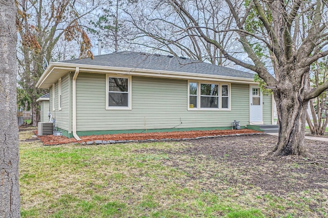 view of home's exterior with a yard, central AC, and roof with shingles