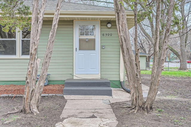property entrance featuring a shingled roof